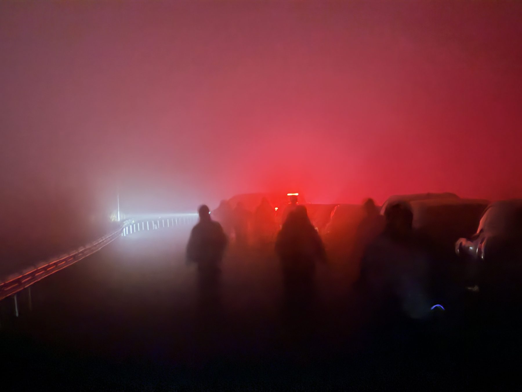 红雾中停在路边的车队和几个模糊的人影